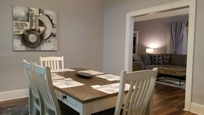 Een eetruimte met een houten tafel en stoelen, een kroonluchter en een schilderij aan de muur.