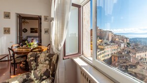 Ein Zimmer mit Esstisch, Stühlen, einer Couch und einem großen Fenster mit Blick auf die Stadt.