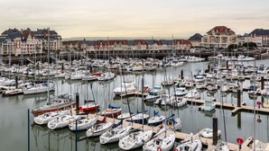 Un port de plaisance où sont amarrés de nombreux bateaux, entouré d’immeubles à étages aux styles architecturaux variés.