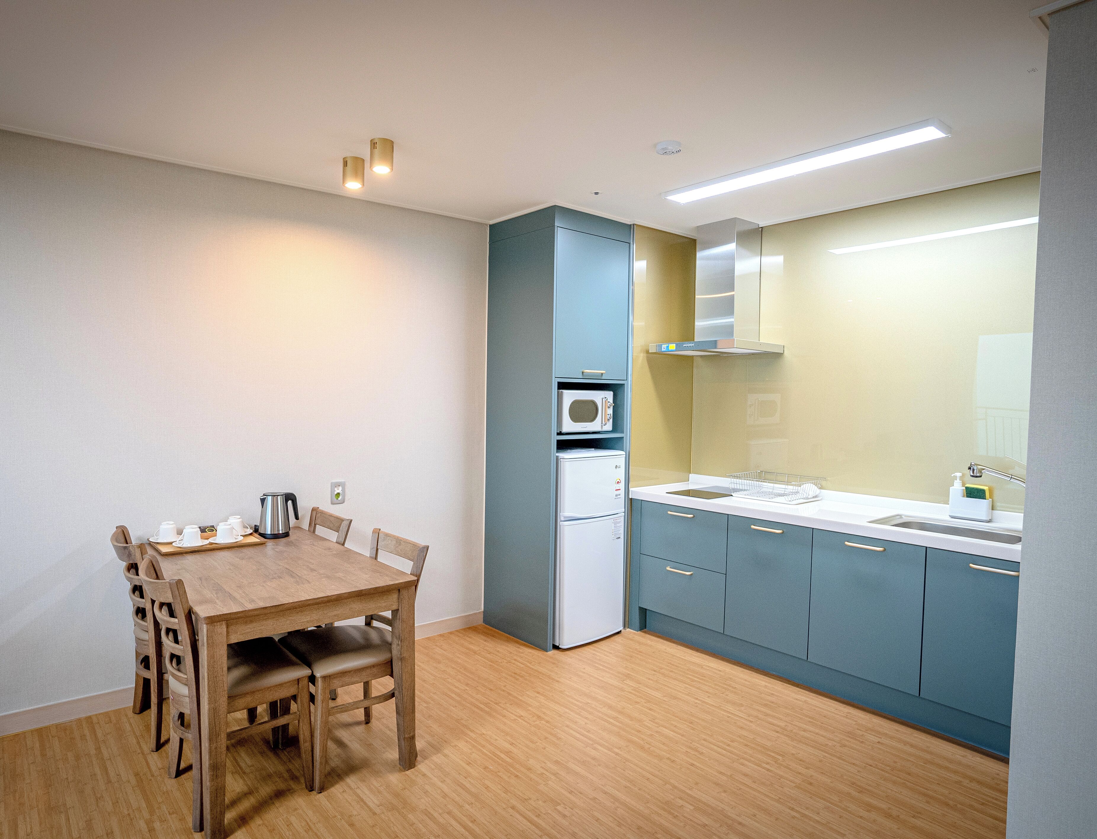 Een kleine keuken met een houten eettafel, een magnetron en een koelkast.