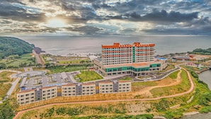 Un hotel costero con varias construcciones, un estacionamiento y vistas al mar.