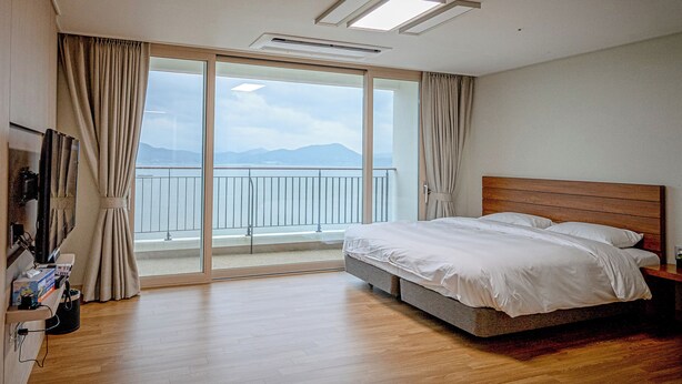 Una habitación de hotel con cama, televisión y balcón con vista al mar.