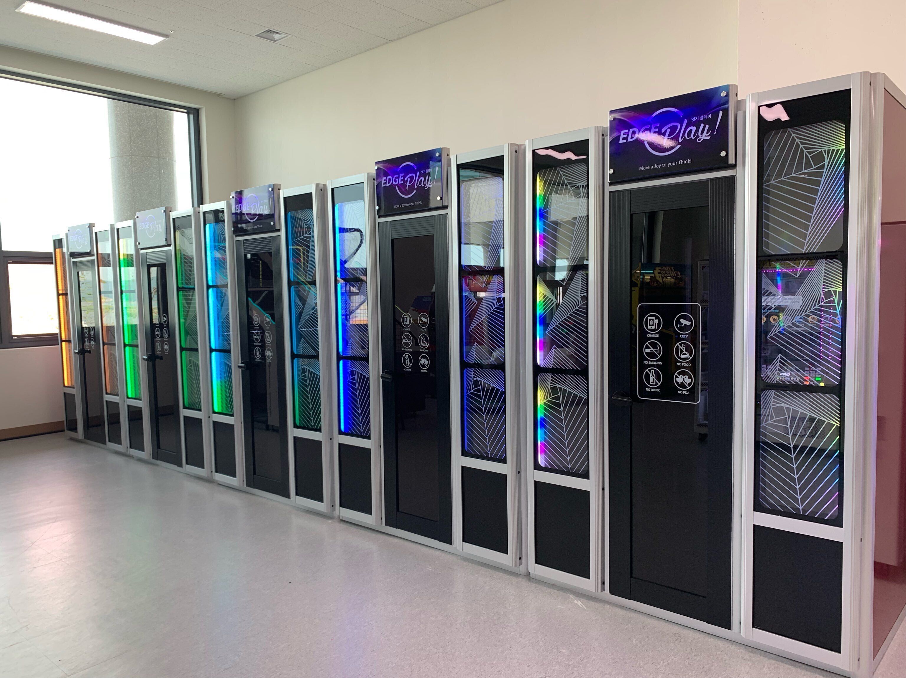 A row of vending machines with colorful LED displays and various icons indicating available items.