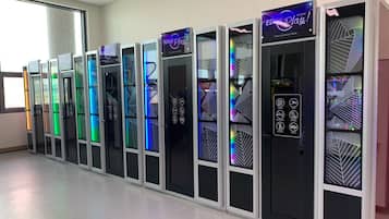 A row of vending machines with colorful LED displays and various icons indicating available items.