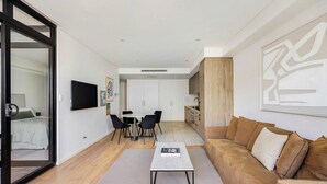 A modern living room with a sofa, a coffee table, and a dining area with chairs and a table.