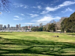A park with a grassy field, trees, and a city skyline in the background. - Modern, Private Luxury Apartment - Harbourside (Darlinghurst)