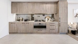 A modern kitchen with light wood cabinetry, stainless steel appliances, and a clean, minimalist design.