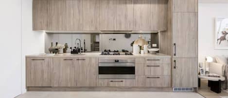 A modern kitchen with light wood cabinetry, stainless steel appliances, and a clean, minimalist design.