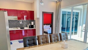 A modern hotel room with a dining area, kitchen, and a view of the pool. - Davinci Pool Villa (Pattaya)