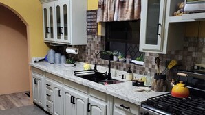 Una cocina con armarios blancos, una estufa y un lavabo.