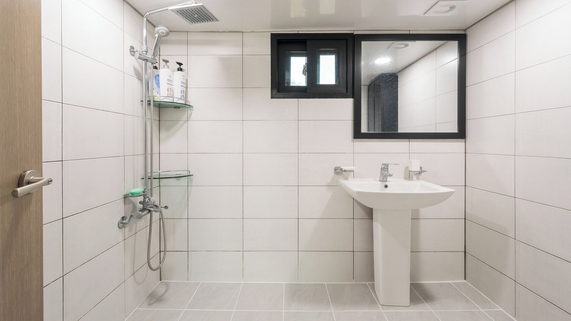 A modern bathroom with a shower, glass shelf, and a sink.
