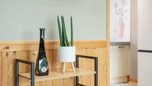 Una estantería de madera con una botella y una maceta blanca con plantas verdes.