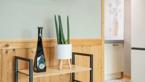Een houten plank met een fles en een witte pot met groene planten.