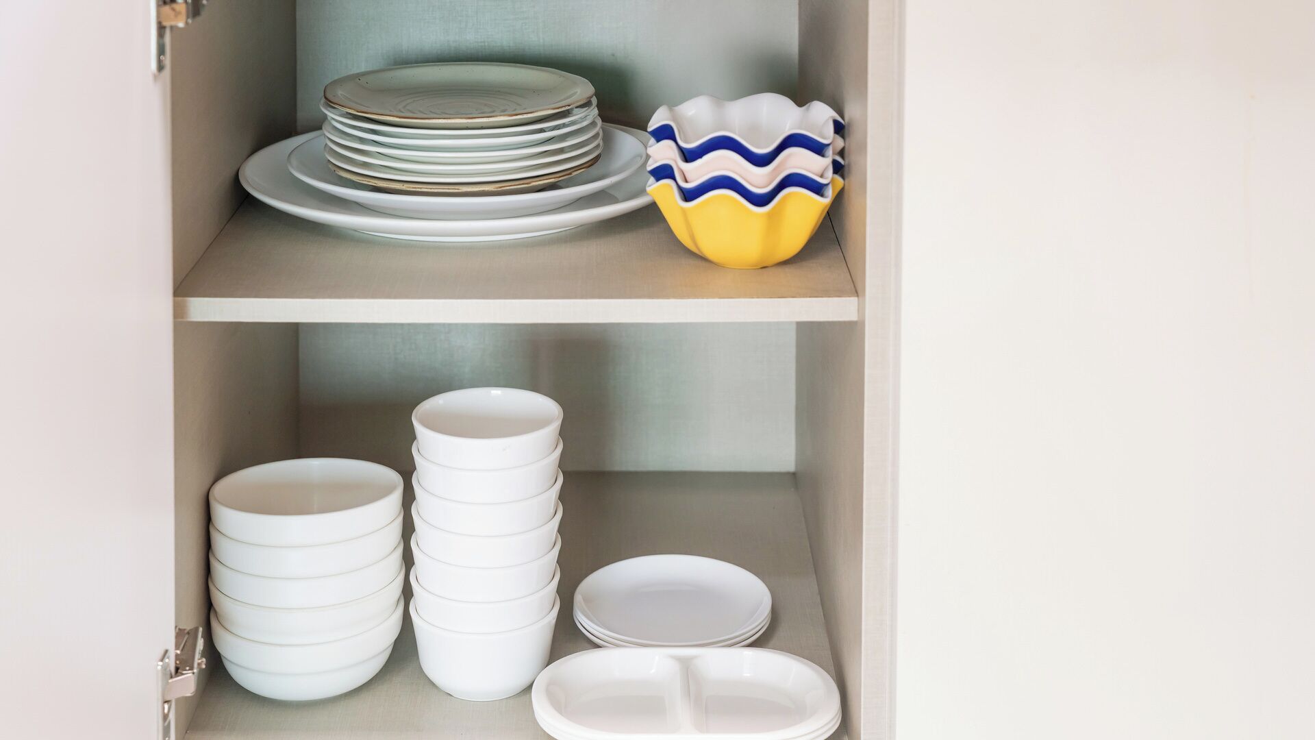 A cabinet with stacked plates and bowls.