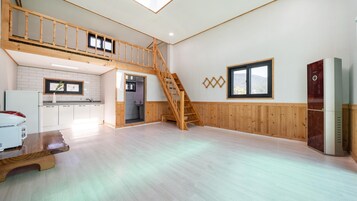 Un espacio habitable amplio con una escalera de madera, una cocina con armarios blancos y un ventanal que ofrece vistas al exterior.