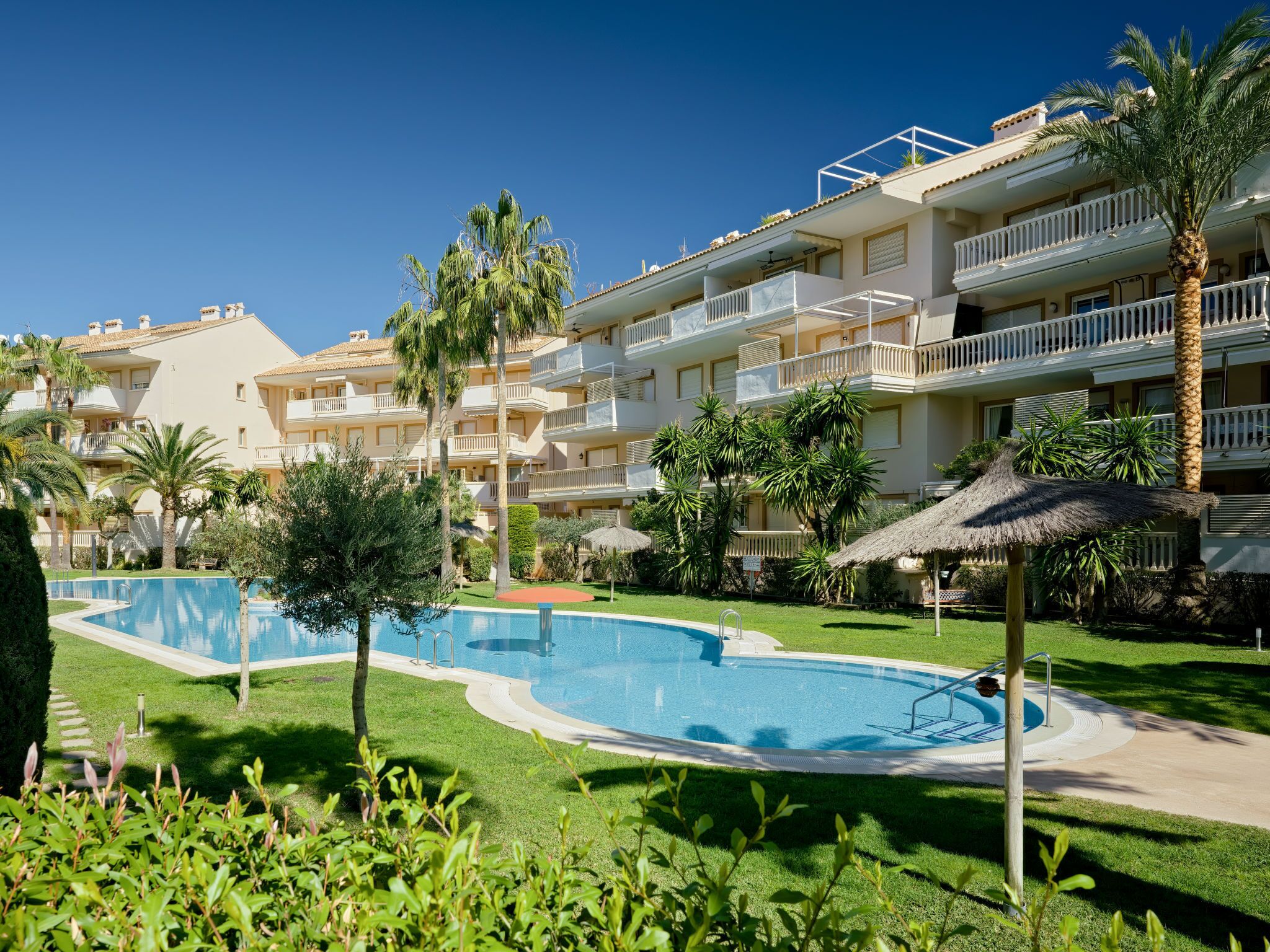 A resort with a swimming pool, palm trees, and a building with balconies.
