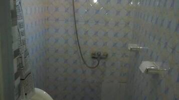 Een kleine badkamer met toilet, douche en een blauwe wastafel.