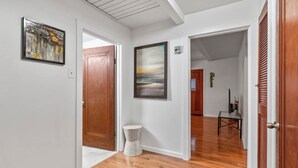 A hallway with wooden flooring, a door, a framed painting, and a small round table. - Cute ranch house -quiet & safe -3 BR  1 Bath (Imperial)
