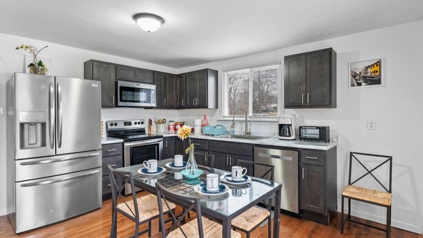 A modern kitchen with stainless steel appliances, dark cabinetry, and a glass dining table with chairs. - Cute ranch house -quiet & safe -3 BR  1 Bath (Imperial)