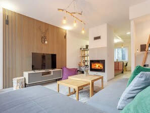 Una sala de estar moderna con un televisor de pantalla plana, una chimenea y un comedor.