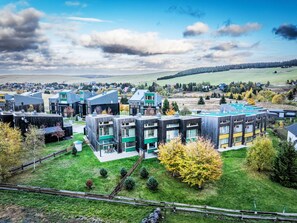 Un área residencial moderna con varios edificios de apartamentos, espacios verdes y una vista despejada del campo circundante.