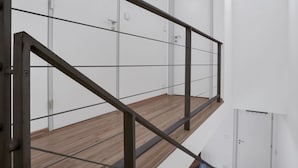 Una escala moderna amb barana metàl·lica i graons de fusta, que mena a una porta blanca a dalt.