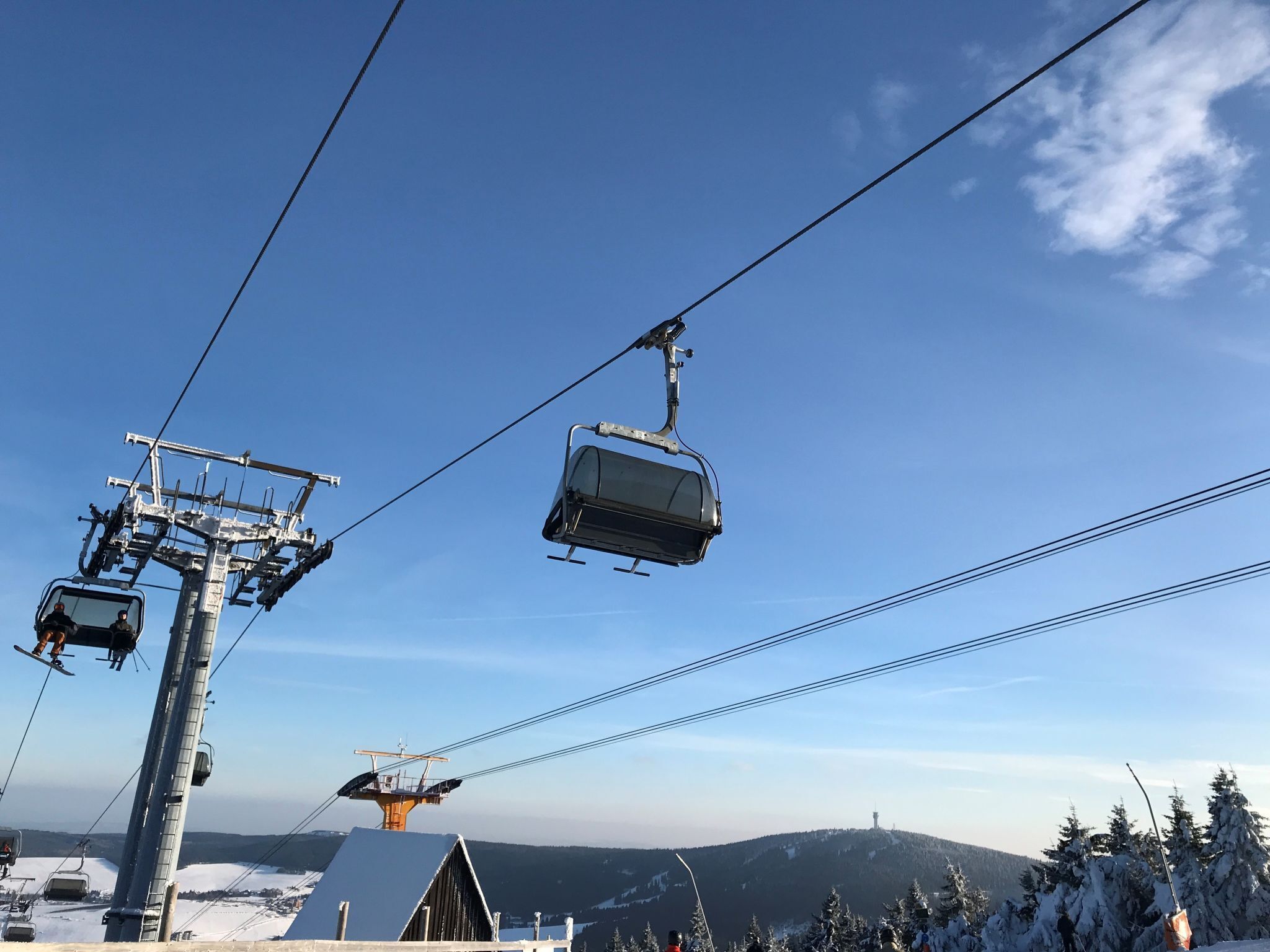A ski lift with cabins suspended by cables against a clear blue sky.