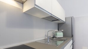 Une cuisine moderne équipée d’une plaque de cuisson à induction noire, d’un évier avec un robinet, d’un grille-pain et d’un réfrigérateur.