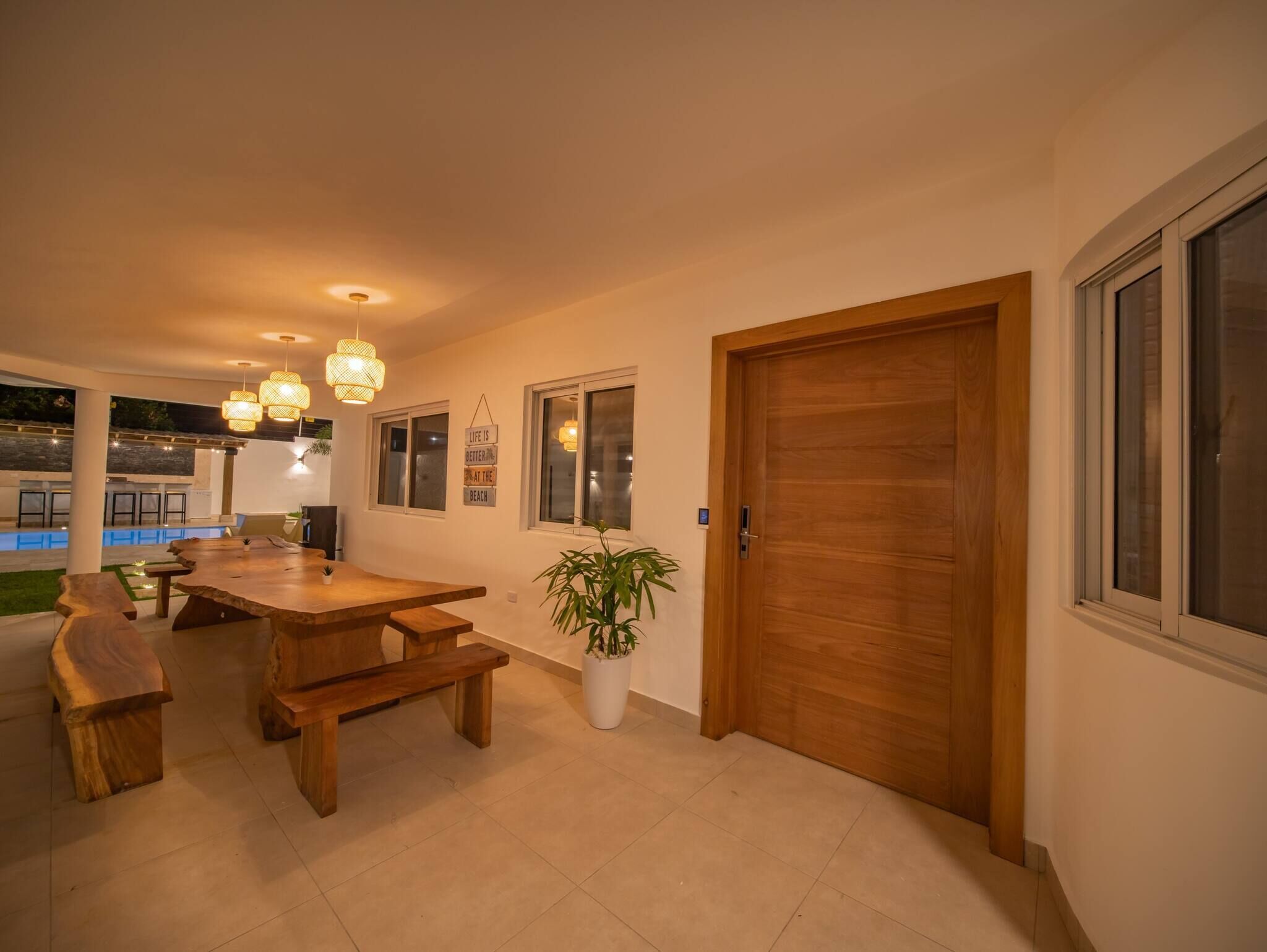 A dining area with a wooden table and benches, a potted plant, and a door with windows.