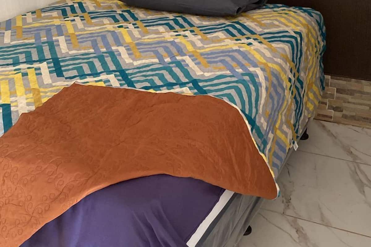 Una cama individual con una colcha estampada y una manta marrón.