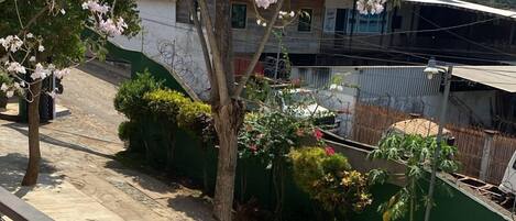 Un balcón con barandilla de metal que da a una zona residencial con árboles y un edificio.