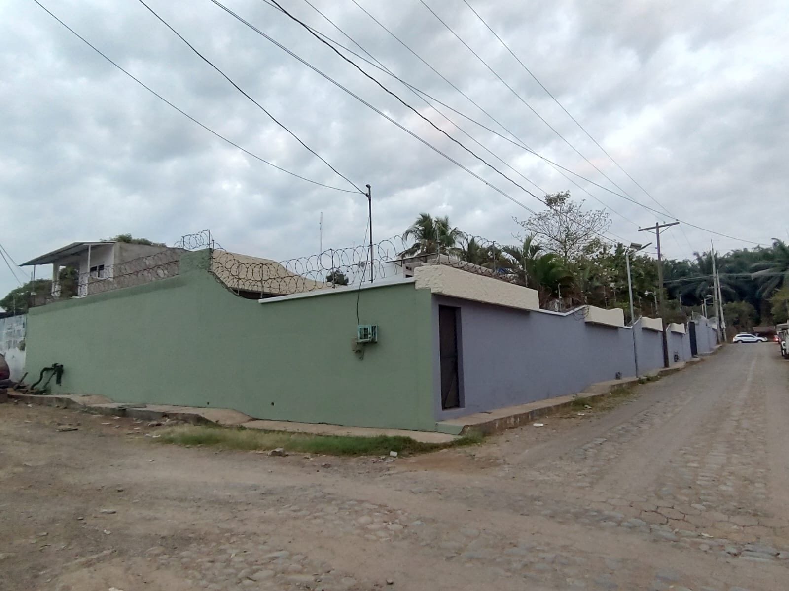 A residential street with houses, a dirt road, and power lines.