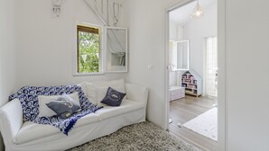 Een witte kamer met een witte bank, een spiegel en een raam.