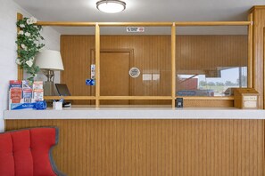 A reception desk with a wooden panel design, a 'No Smoking' sign, a 'Pet Friendly' sign, and a 'Key Drop' box. - First Inn By OYO Quinter Hwy 70 (Quinter)