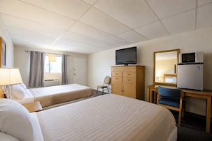 A hotel room with two beds, a television, a refrigerator, a desk with a chair, and a mirror. - First Inn By OYO Quinter Hwy 70 (Quinter)
