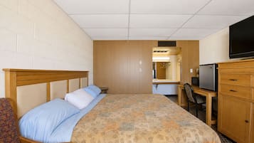 A hotel room with a bed, a desk with a chair, a television, and a mirror.