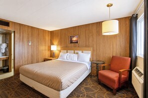 A hotel room with a bed, a chair, a lamp, a picture on the wall, and a radiator.