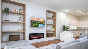 A modern living room with a fireplace, a flat-screen TV, and a sofa. - Pristine Fully Renovated House - 12min from Disney Parks (Kissimmee)