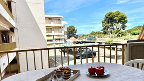 A balcony with a table set for breakfast, a view of the street, and a building in the background. - International loft, air-conditioned with pool and beach (cambrils)