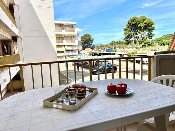 A balcony with a table set for breakfast, a view of the street, and a building in the background. - International loft, air-conditioned with pool and beach (cambrils)