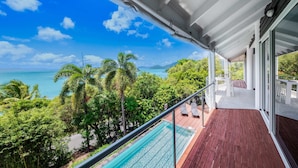A balcony with a view of the ocean and palm trees. - Seascape on Shutehaven (Shute Harbour)