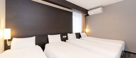 A hotel room with three single beds, a dark headboard, a wall-mounted air conditioner, and two bedside lamps.
