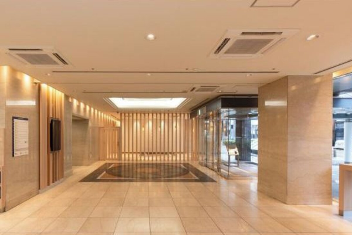 A modern hotel lobby with a central open space, wooden paneling on the walls, and a glass elevator.