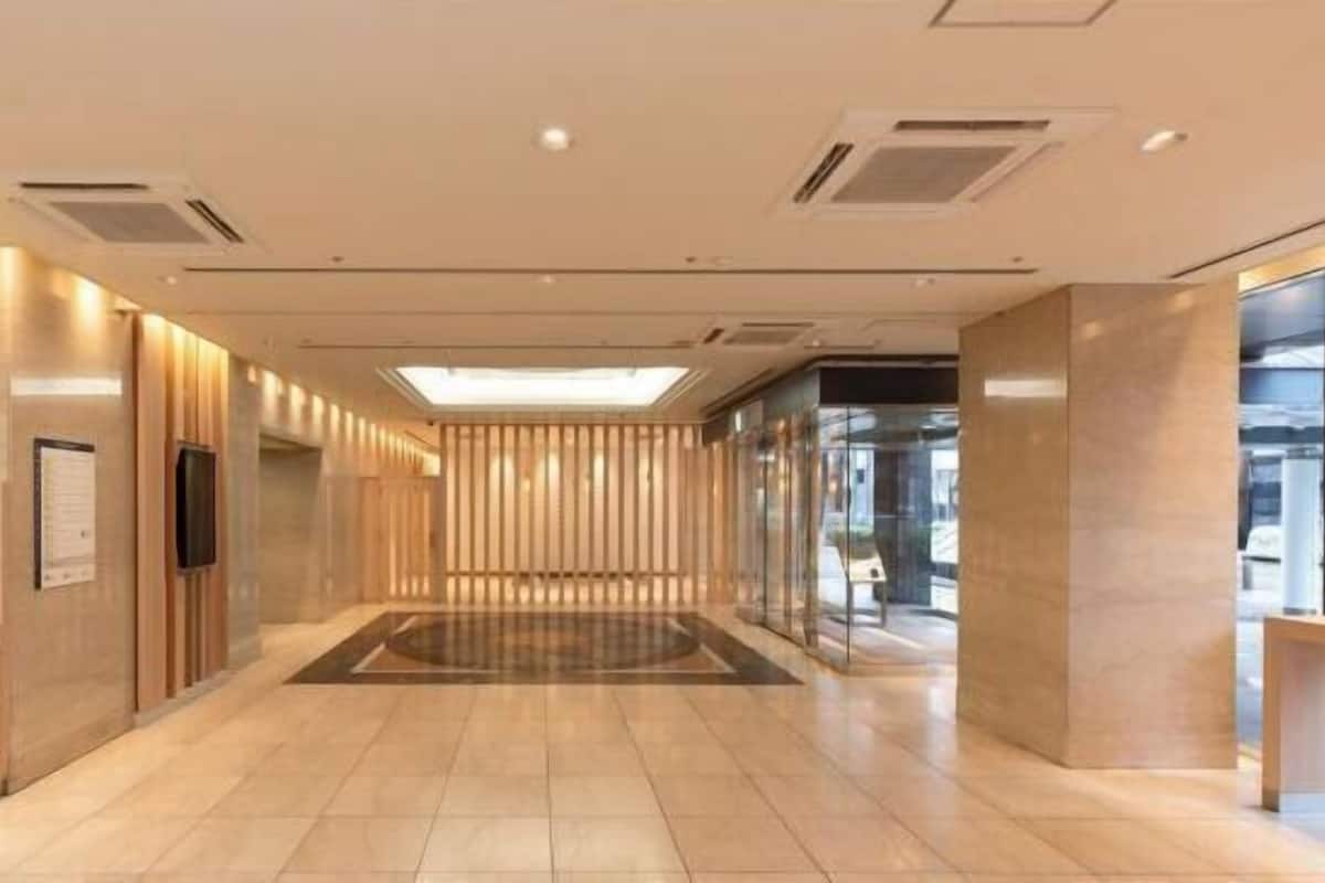 A modern hotel lobby with a central open space, wooden paneling on the walls, and a glass elevator.