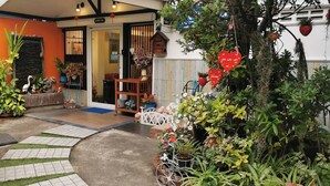 A garden entrance with a pathway, potted plants, and a wooden bench. - BAANFAHSAI ANU (Bangkok)