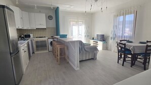 A modern kitchen with a dining area, a washing machine, a microwave, and a TV. - CHEZ CHOUCAS - LA MAISON DE CHOUCAS (Portoferraio)