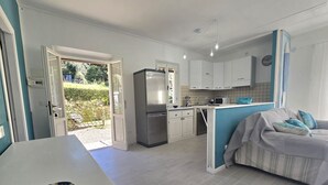 A modern kitchen with white cabinets, a built-in refrigerator, and a microwave. There's a dining area with a white table and a decorative bowl. - CHEZ CHOUCAS - LA MAISON DE CHOUCAS (Portoferraio)