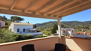 A covered outdoor area with a view of a hillside and buildings.