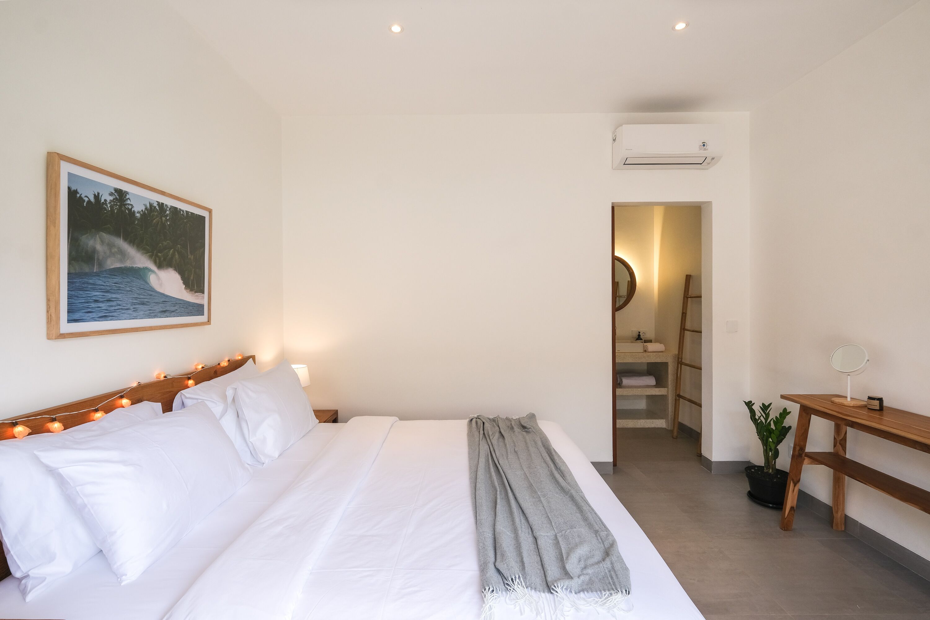Een slaapkamer met een bed, nachtkastje en een schilderij van een golf.