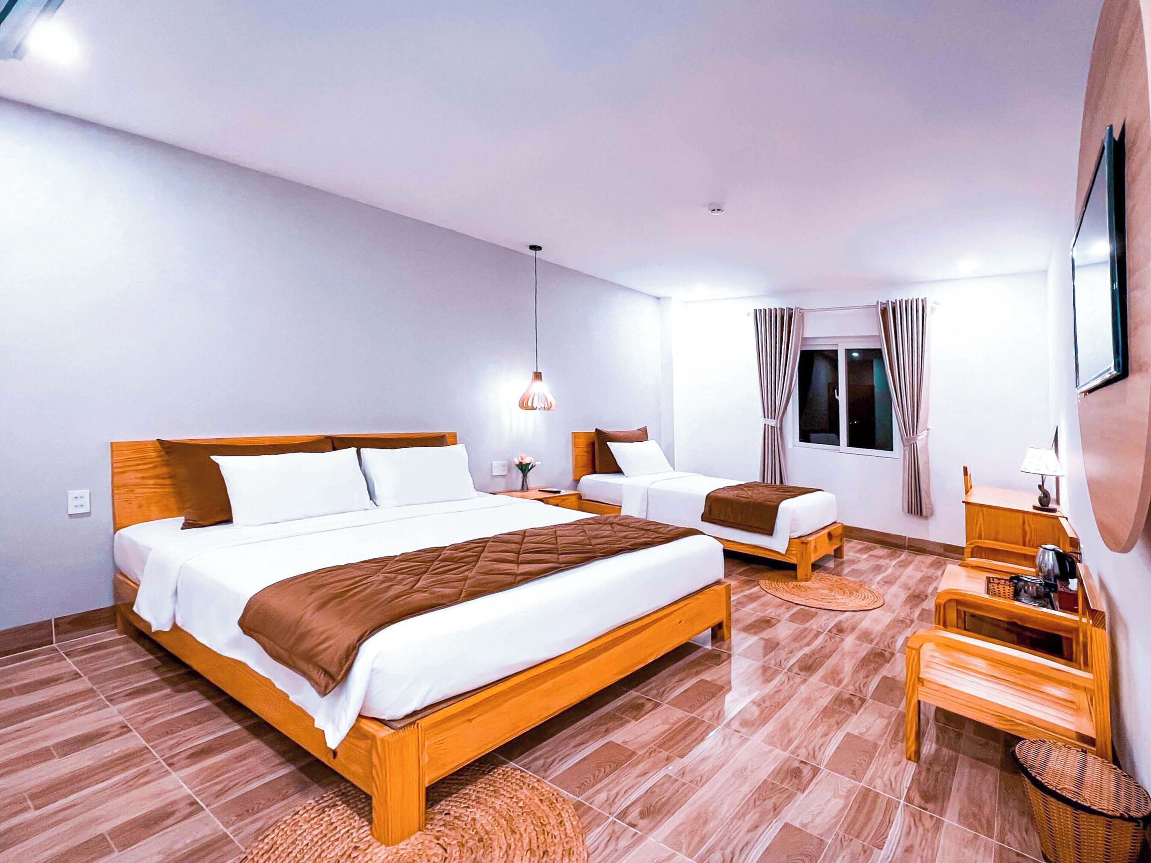 Una habitación de hotel con una cama grande, una cama más pequeña, un escritorio y una silla.